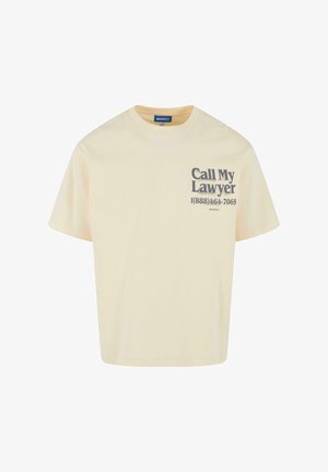 Kreemivärvi puuvillane t-särk lühikeste varrukatega. Omab trükitud graafikat, millel on tekst "Kutsu mu advokaat" ja telefoninumber tumedashalli värviga.