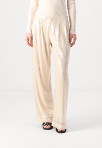 Crèmekleurige broek met wijd gemaakte pijpen, versierd met pailletten, voorzien van een soepele tailleband en een zachte textuur die het licht weerkaatst met sprankelende details.
