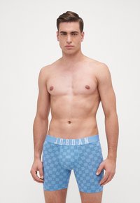 Boxeri albaștri cu un design pattern în nuanțe de albastru deschis, având un elastic pe talie inscripționat cu 'JORDAN.' Construiți dintr-un material moale și elastic.