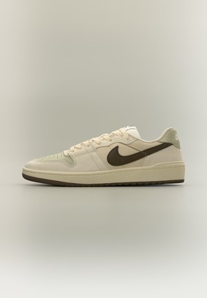 Beiger Nike Sneaker mit niedrigem Schaft, dunkelbraunem Swoosh-Logo und Sohle, Schnürdesign und perforiertem Zehenbereich auf neutralem Hintergrund.