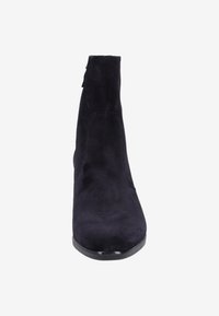 Botines negros de ante hasta el tobillo con un diseño elegante y alto, que presentan una textura suave y una suela negra brillante. Cierre con cremallera en la parte trasera.