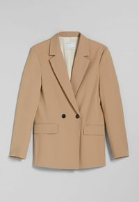Beżowa marynarka dwurzędowa z kontrastowymi czarnymi guzikami, dwoma przednimi kieszeniami, usztywnionymi ramionami i gładkim wykończeniem materiału.