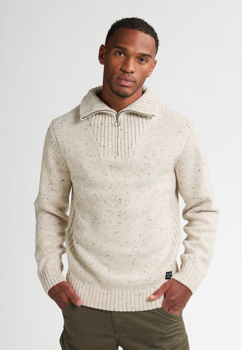 Pullover lavorato a maglia beige con colletto alto e righe, e zip a quarto, caratterizzato da un motivo testurizzato e da sottili punte di colore sparso.
