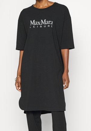 Osoba ubrana w czarną, oversize'ową sukienkę typu T-shirt z białym napisem "Max Mara LEISURE" na piersi oraz czarne spodnie.