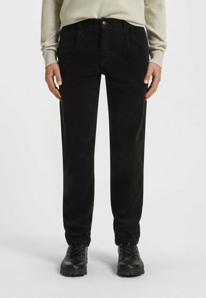 Corduroy pants in black, featuring a straight-leg design with side pockets and a button closure, paired with black lace-up ankle boots.