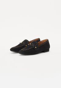 Mocassini in suede nera con borchie dorate, una cintura decorativa, tacco basso a blocco e dettagli cuciti lungo l'apertura.