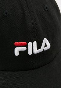 Melnā beisbola cepure, izgatavota no kokvilnas, ar balti izšūtu "FILA" logo un sarkanu akcentu. Iespējo izliekta mala un ventilācijas caurumi.