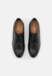 Chaussures en cuir noir avec bout arrondi, design à lacets, surface lisse, semelle intérieure beige et semelle extérieure en caoutchouc.