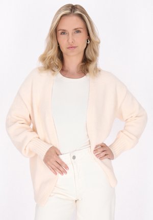 Lichtroze cardigan met een relaxte fit en ribbels aan de mouwen. Gepaard met een witte top en crèmekleurige broek, heeft het een zachte, gestructureerde afwerking.