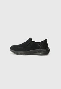 Black slip-on shoes made of breathable mesh with a textured heel and cushioned sole, featuring minimal stitching and a sleek design.