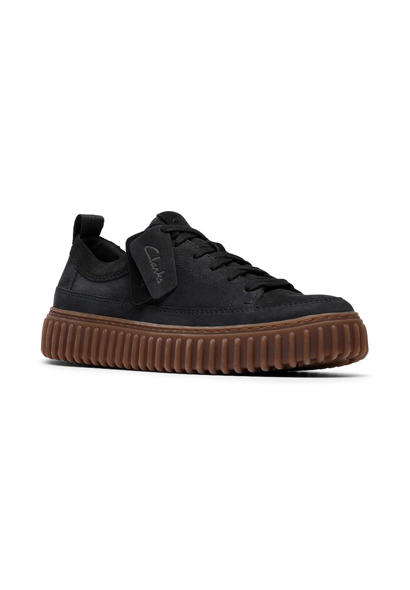 Schwarze Wildleder-Sneaker mit einer strukturierten Gummisohle und runder Zehenpartie. Verfügt über flache Schnürsenkel und ein Etikett mit dem "Clarks"-Logo. Minimalistisches Design.
