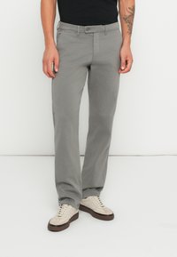 Pantaloni grigi chiari con taglio dritto, realizzati in un materiale morbido. Presentano una chiusura con bottone e passanti per cintura. Abbinati a sneaker beige.