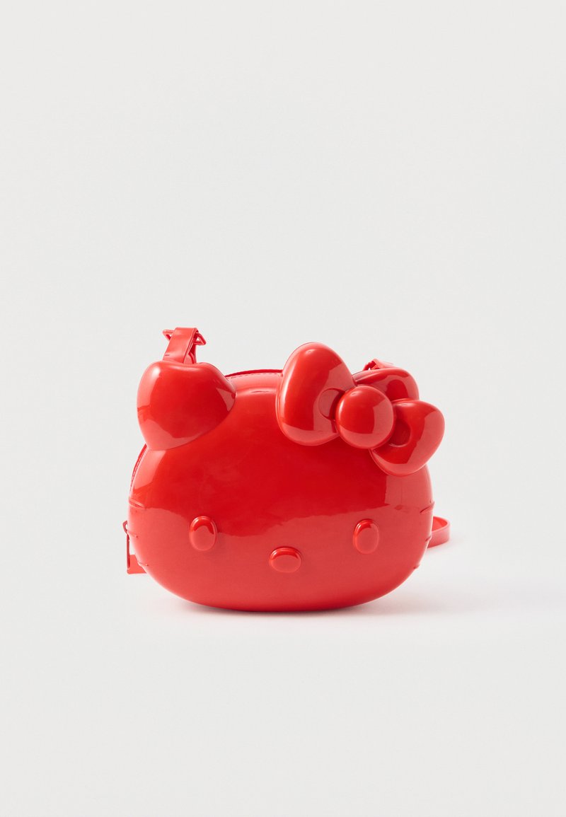 Κόκκινο γυαλιστερό τσαντάκι χιαστί σε σχήμα καρτούν γάτας με φιόγκο και καρδ-form τα αυτιά, σε λευκό φόντο.