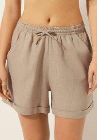 Kneelånga beige shorts i linne, med en elastisk midja och dragsko, sidofickor och uppvikta fållar.