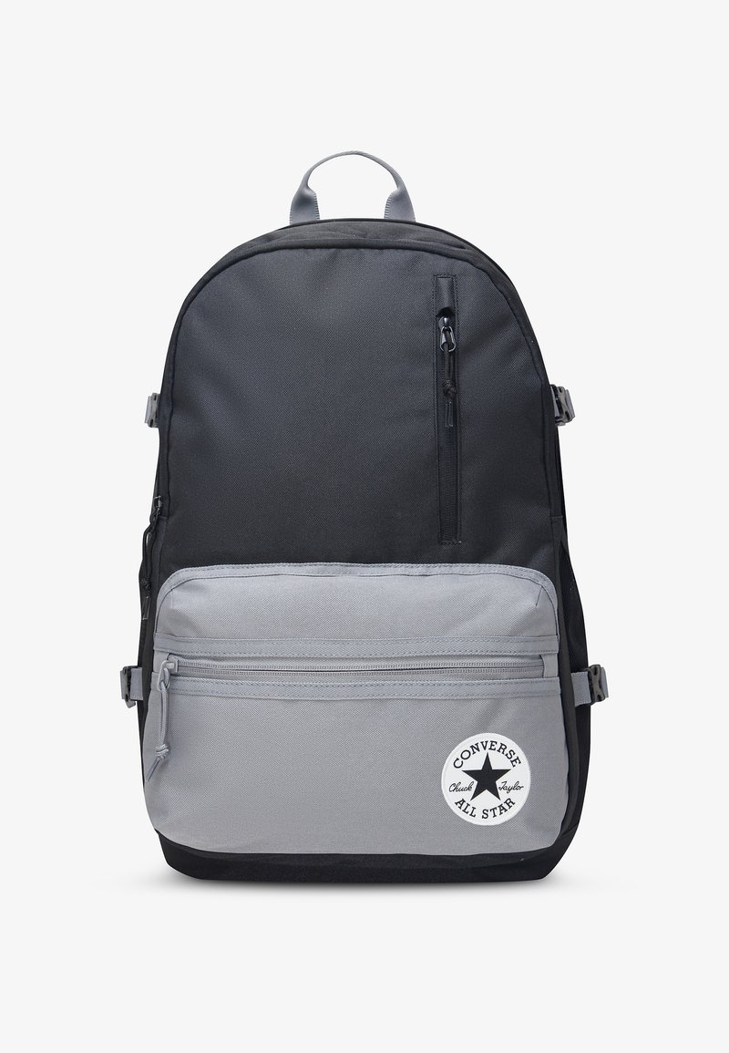 Sac à dos Converse noir et gris avec poche avant zippée et écusson rond avec logo en bas à droite.