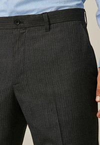 Dark gray pinstripe trousers with a smooth finish, featuring a button closure, belt loops, and side pockets. Tailored fit design.