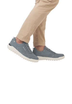 Gray suede sneakers with white rubber sole and textured detailing. Features laces and a pull tab at the heel. Worn with beige pants.