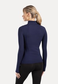 Marineblauw sportief shirt met lange mouwen, hoge kraag, aansluitende pasvorm en gladde textuur, gecombineerd met zwarte legging.