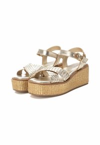 Sandali a wedge metallici oro con cinghie intrecciate, punta aperta, fibbia regolabile alla caviglia e piattaforma in juta testurizzata. Suola piatta e soletta imbottita.