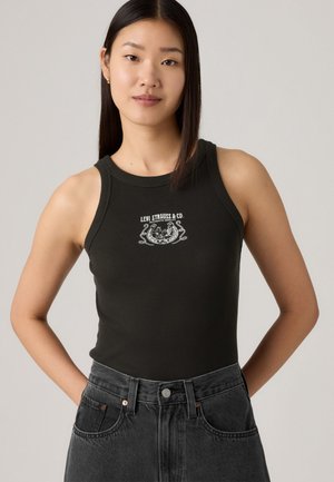 Mörkgrön ribbad linne med rund halsringning och vitt grafiskt trycklogotyp i mitten, parat med högmidjade mörk denimjeans.