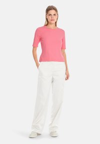 Fuchsia knit top with short sleeves paired with loose white cargo pants. The outfit features a round neckline and a relaxed fit.