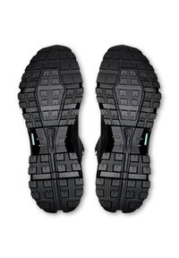 Schwarze Gummisohlen mit tiefem Profil und strukturierten Oberflächen, entworfen für guten Halt, mit verstärkten Kanten und robuster Bauweise.