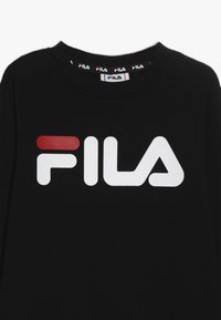 Felpa nera con un grande logo FILA bianco e rosso. Il colletto è a coste con una fascia logo a contrasto. Materiale in cotone morbido.