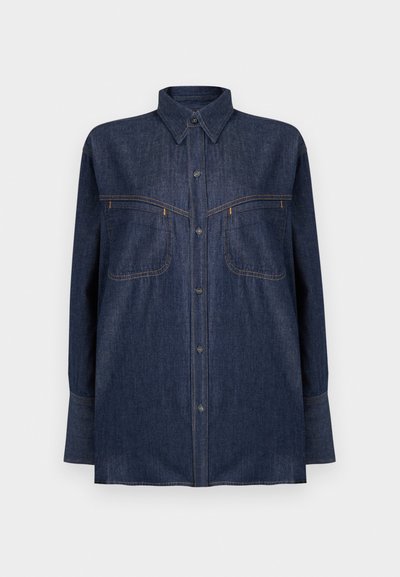 Tmavomodrá denimová košeľa s dlhými rukávmi, zapínaním na gombíky vpredu, dvoma náprsnými vreckami a kontrastným oranžovým prešívaním. Klasický golier a voľný strih.