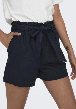 Mørkeblå shorts med en flæsekant og et stofbånd. Har sidelommer og en lige pasform, lavet af et struktureret materiale.