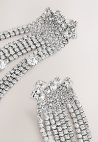 Silver bracelet with multiple rows of clear rhinestones, featuring various sizes and shapes, with a smooth metallic clasp.