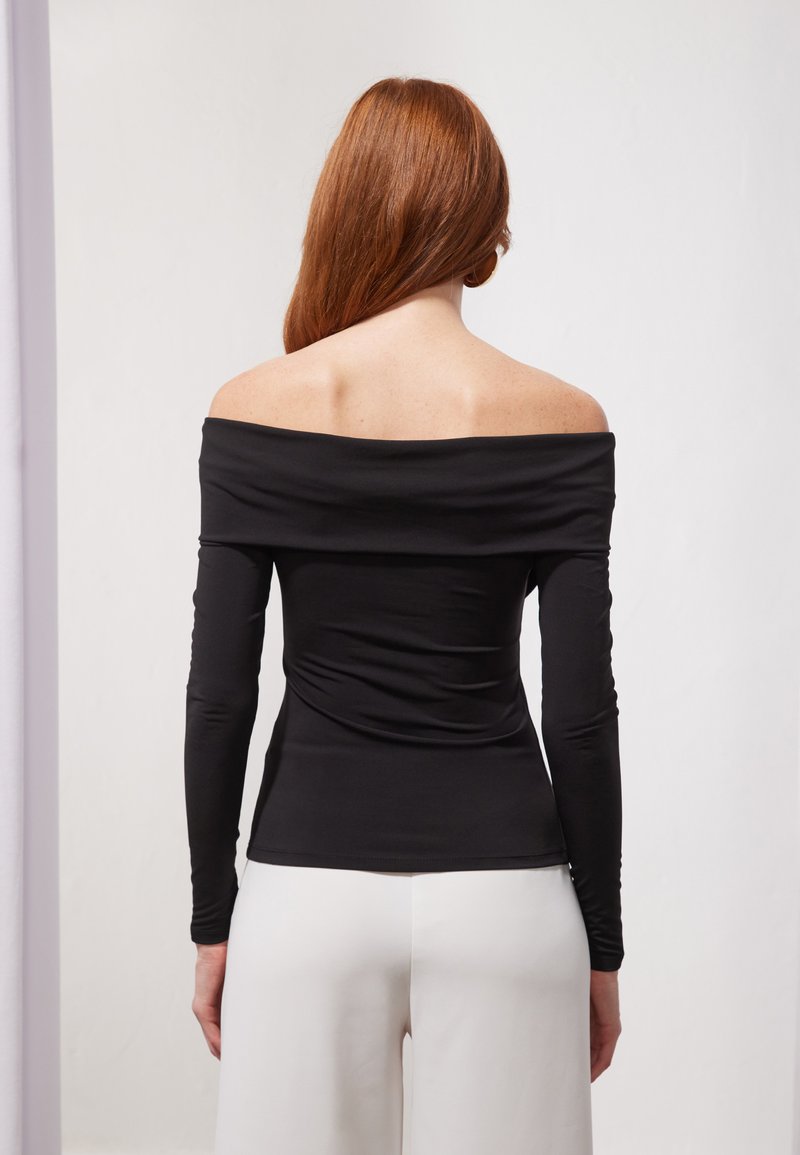 Schwarzes, schulterfreies Oberteil mit langen Ärmeln aus glattem Stoff, das eine figurbetonte Silhouette hat und sanfte Raffung im Rücken aufweist.