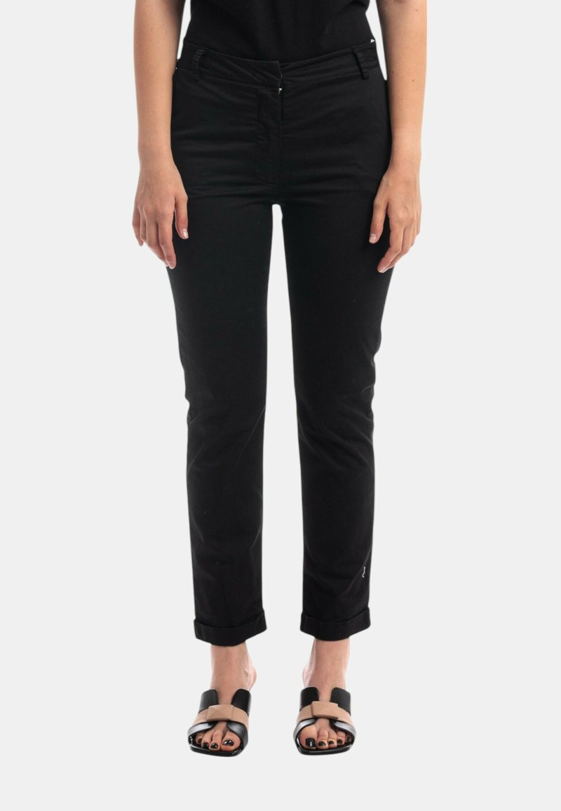 Pantaloni neri aderenti con passanti per cintura, tasche frontali e risvolti, realizzati in tessuto twill. Abbinati a sandali piatti a ciabatta.