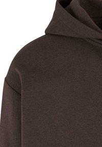 Sudadera marrón oscuro con una textura suave, presenta una capucha grande y un corte relajado. El material parece suave y ligeramente elástico.