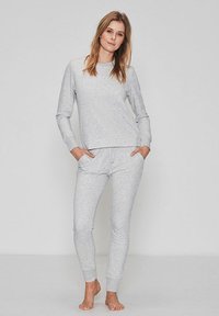 Conjunto de loungewear en gris claro, hecho de un material suave, que incluye una parte superior de manga larga con cuello redondo y pantalones ajustados con cintura elástica.