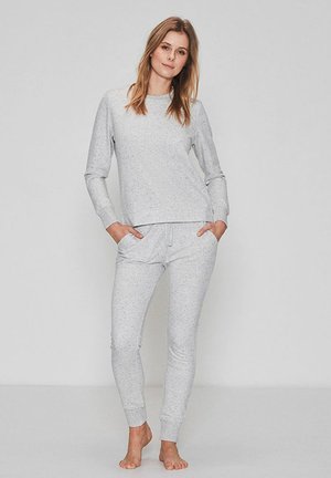Lys grå loungewear sæt lavet af blødt materiale, der har en langærmet bluse med rund hals og tapered bukser med elastisk talje.