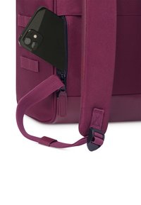 Bordeauxfarbener Rucksack mit einer Reißverschlusstasche, in der ein schwarzes Smartphone teilweise sichtbar ist. Verstellbarer Schultergurt mit einem Kunststoffschnallen.
