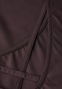 Tissu de jersey marron avec une texture lisse, présentant des détails de couture et des éléments de design superposés.