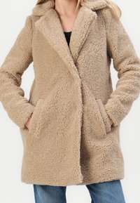 Béžový kabát z umělé beránkové kožešiny s vykrojeným límcem, dlouhými rukávy, bočními kapsami a měkkým texturovaným povrchem. Neformální design, střední délky.