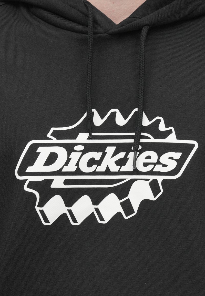 Sudadera con capucha negra con un logo blanco con detalles que recuerdan a engranajes que dice "Dickies". Cordones ajustables en el cuello. Textura de tela suave.
