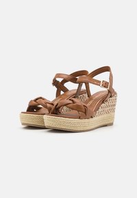 Sandali wedge in pelle marrone con cinghie intrecciate, piattaforma in juta intrecciata e dettaglio intrecciato nell'area delle dita. Chiusura con fibbia sul lato.