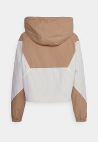 Cropped jacket with a tan and white color block design, featuring a hood, elastic cuffs, and a smooth, lightweight fabric texture.