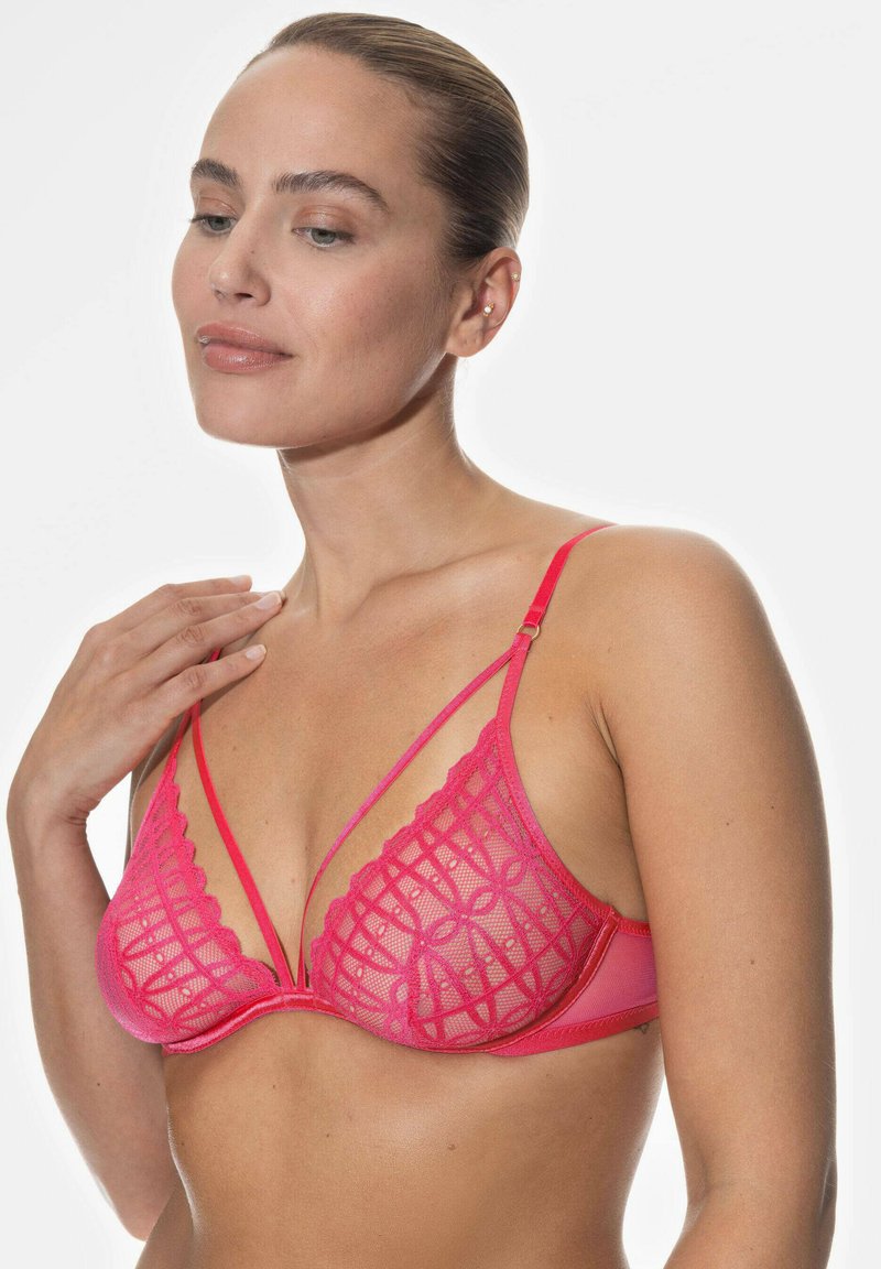 Rosa spets-bh med ett geometriskt mönster, underwire-stöd och justerbara axelband. Designen inkluderar genomskinlig mesh och vågiga kanter.