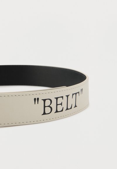 Μπεζ δερμάτινη ζώνη με μαύρο εσωτερικό και μαύρο τυπωμένο κείμενο "ΖΩΝΗ" πλαισιωμένο από εισαγωγικά στην εξωτερική πλευρά.