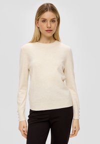 Hellbeige Strickpullover mit rundem Halsausschnitt, langen Ärmeln und dekorativen Knöpfen an den Bündchen. Glatte Textur, taillierte Passform.