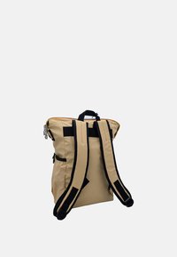 Beżowy plecak z czarnymi paskami, kontrastowym żółtym zamkiem błyskawicznym i bocznymi kieszeniami. Gładka tekstura, usztywniony kształt i górny uchwyt do noszenia.