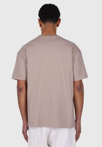 Short-sleeve t-shirt in light beige cotton, features a crew neckline and relaxed fit, with a smooth texture and minimalistic design.