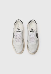 Zapatillas con parte superior de cuero sintético gris y blanco, caja de dedos perforada, acentos negros y cordones blancos. Presenta un logo en el lateral.