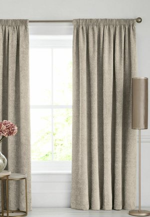 Beige strukturierte Vorhänge bedecken ein Fenster, mit einer hohen beigen Stehlampe rechts und einem kleinen Tisch mit rosa Blumen in einer klaren Vase links.