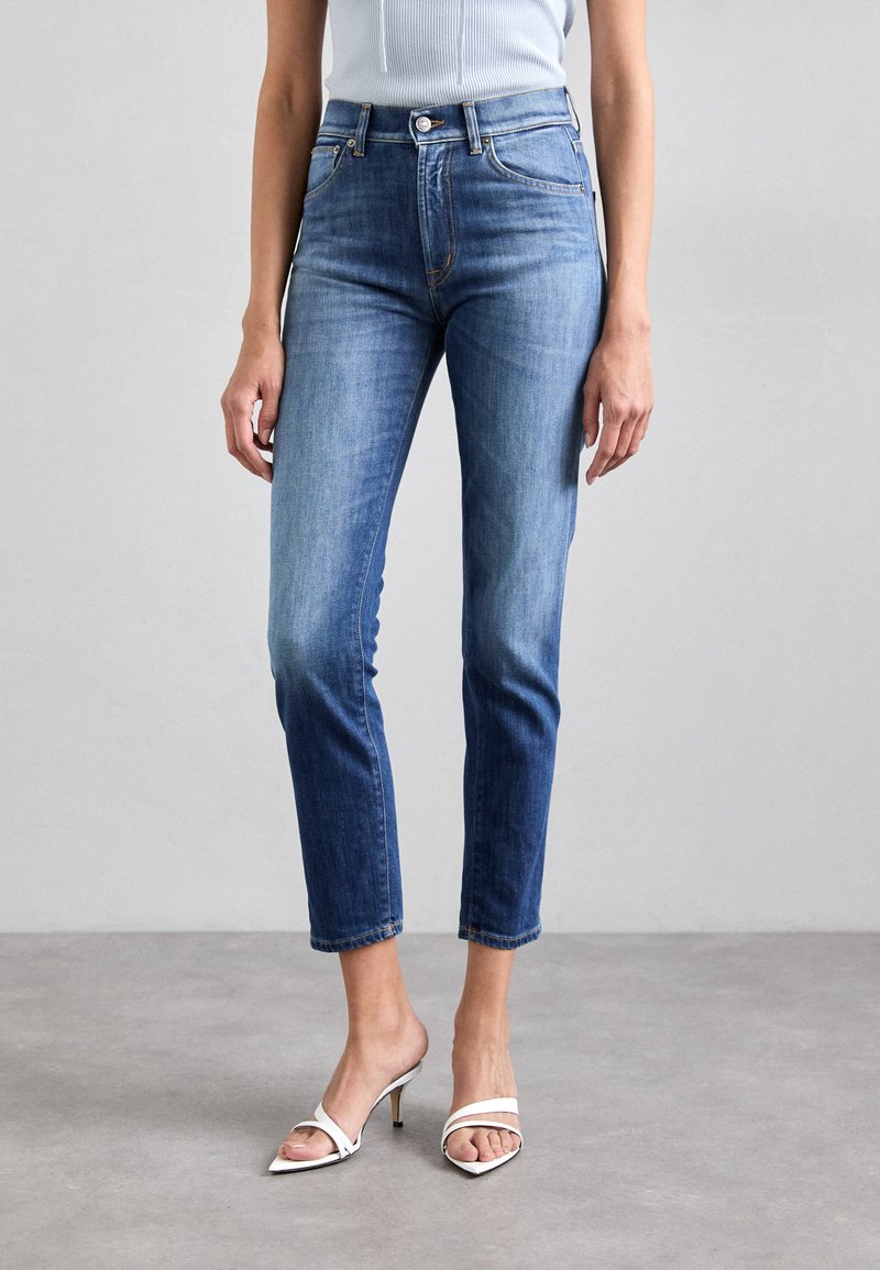 Jeans de denim azul con un ajuste slim, cintura de media altura y longitud cortada. Presentan un cierre de botón y un ligero desvanecimiento en los muslos.