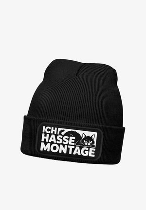 Black knitted beanie featuring a ribbed texture and a rectangular patch with a black and white cat illustration and German text.